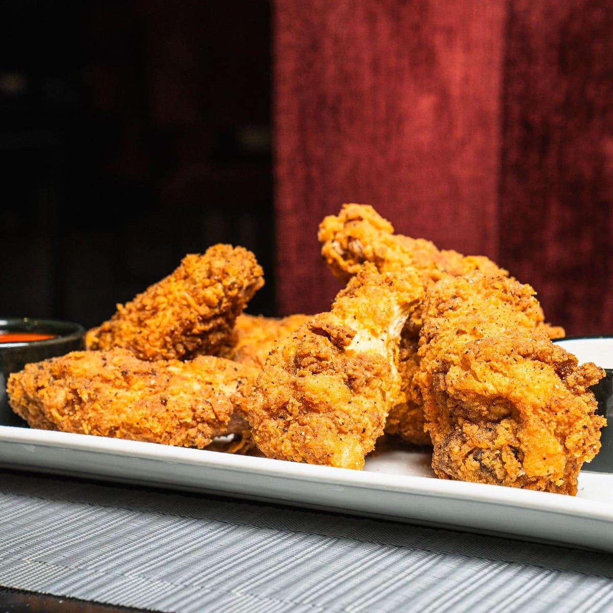 Plate of crispy chicken wings with dipping sauces at Tuscan Cove